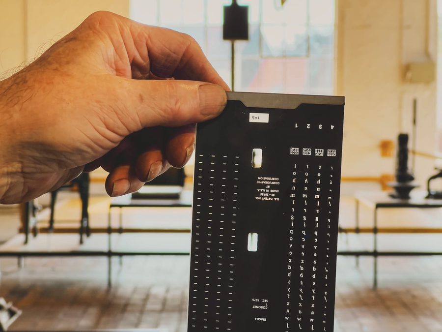 A hand holding the film version of the Coronet typeface from a Compugraphic EditWriter 7500 phototypesetter.
