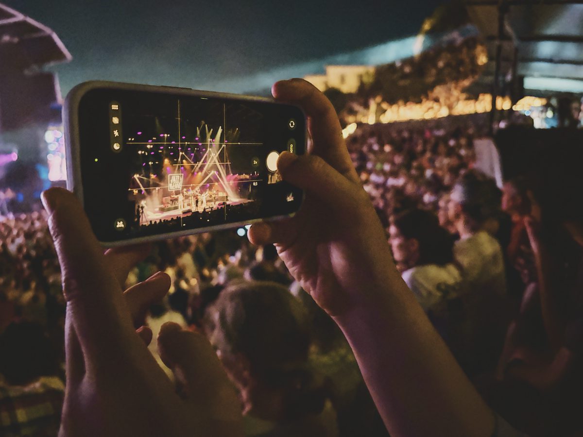 Someone taking a picture of a concert with a smartphone. Image Anthony Nelzin-Santos.
