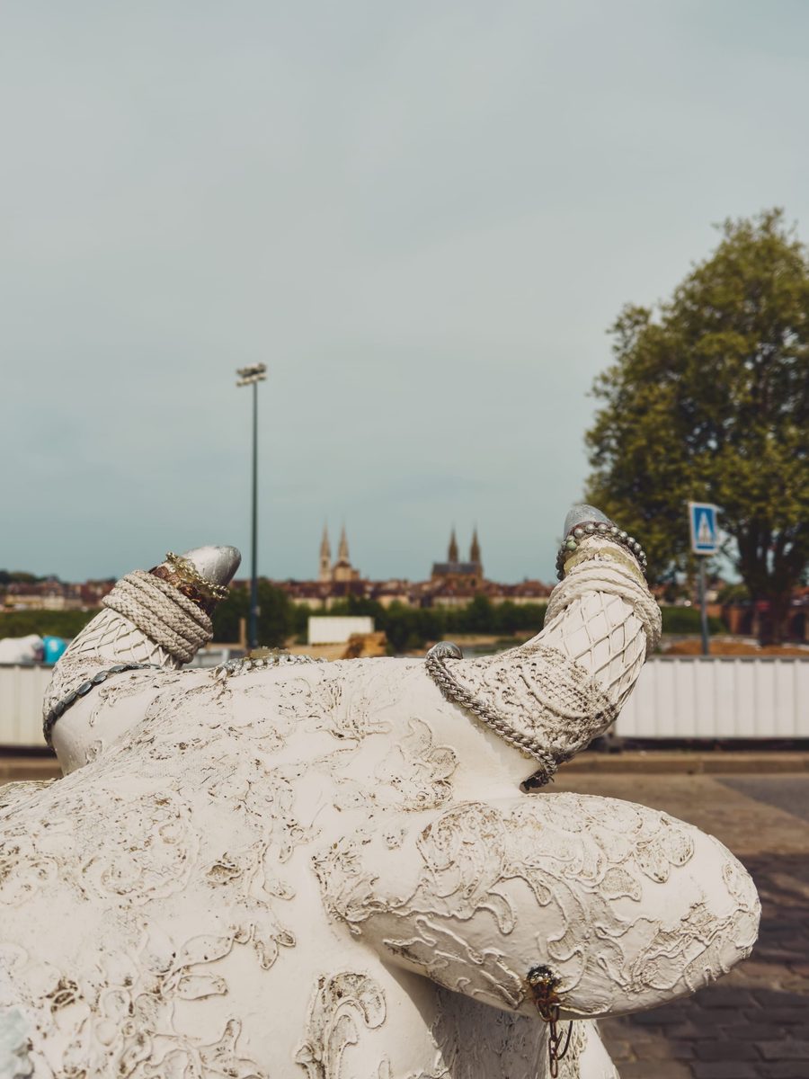 A distant view of Moulins’s churches from between the horns of a statue of a cow.