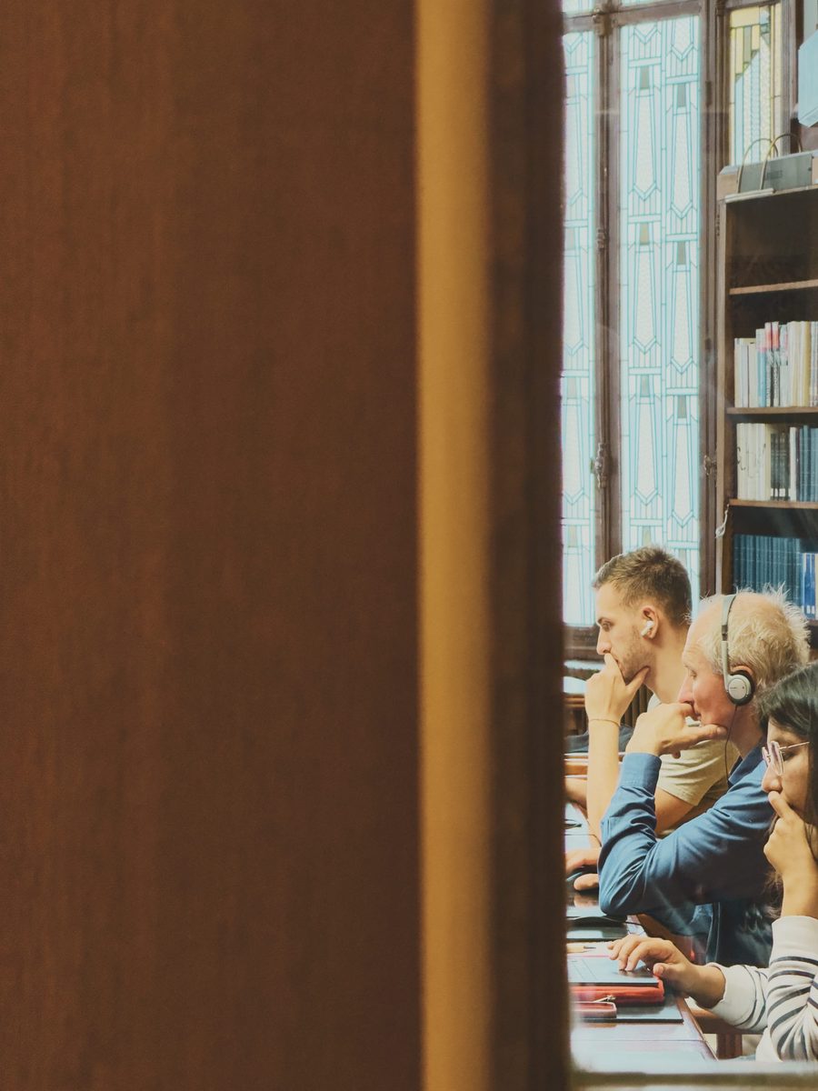 People working at the library, seen through a gap in a door.