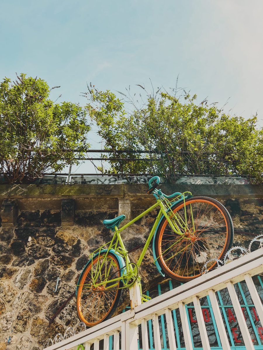 A multi-coloured bike hoisted on top of a bike shop’s entrance grid.