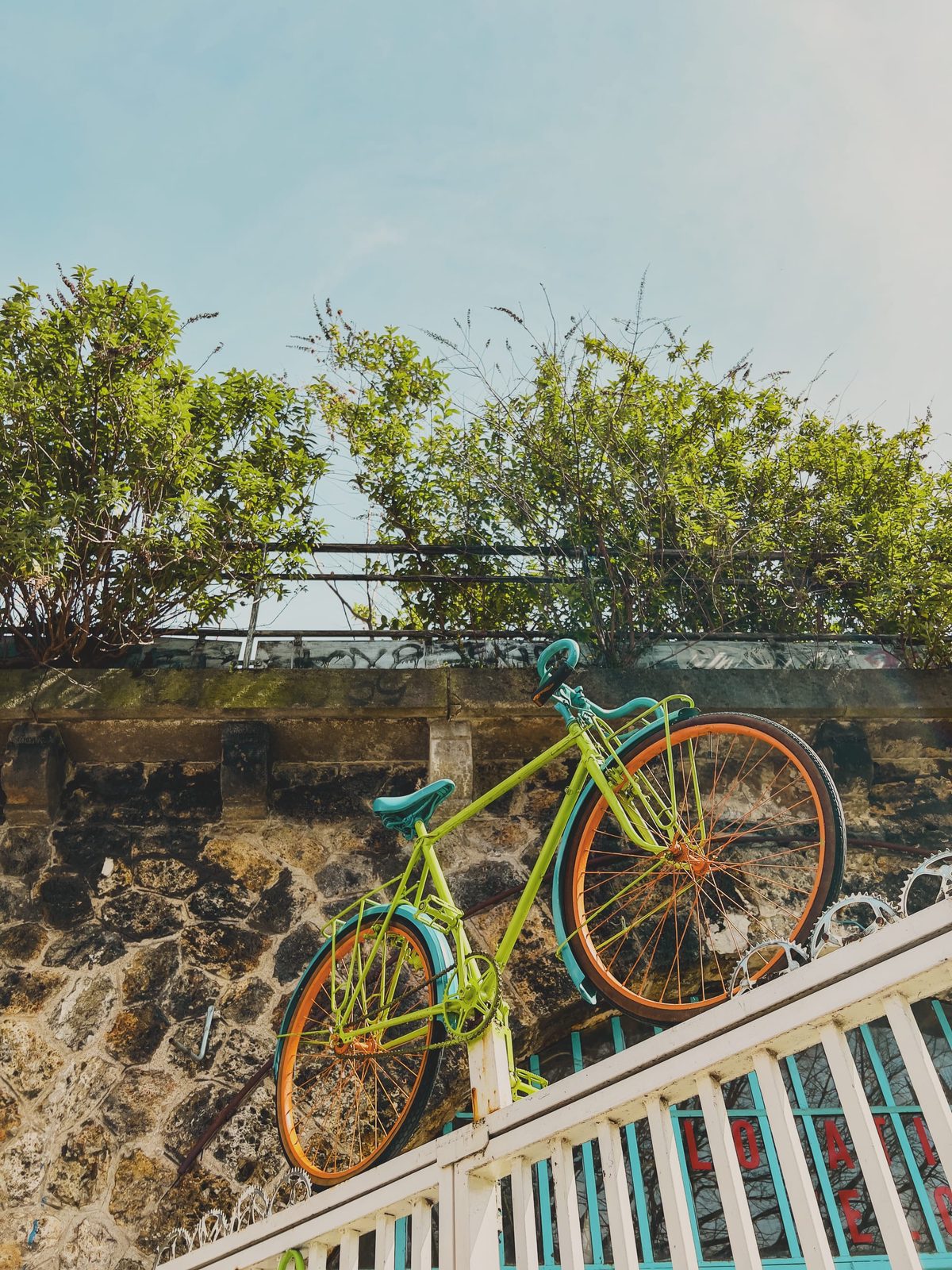A multi-coloured bike hoisted on top of a bike shop’s entrance grid. Image Anthony Nelzin-Santos.